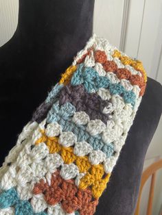 a multicolored crocheted scarf on a mannequin