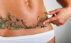 a woman's stomach with tattoos on it and her hand touching the side of her stomach