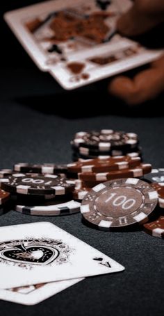 playing cards and chips on a table with two hands reaching for the winning chip in front of them