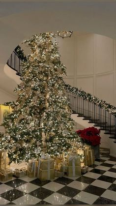 a decorated christmas tree in the middle of a room with presents on the floor and stairs