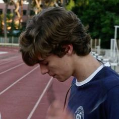 two young men standing next to each other on a track