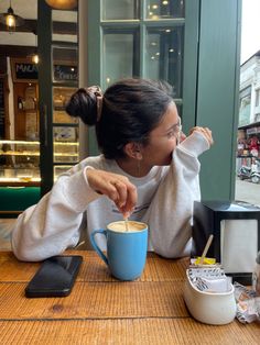 a woman sitting at a table with a cup of coffee