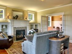 a living room filled with furniture and a fire place in front of a mirror on the wall