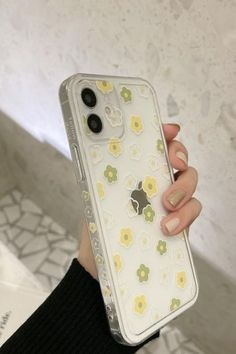 a woman holding up her phone case with flowers on it