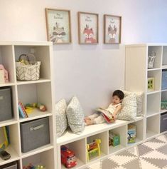 a little boy sitting on top of a white book shelf filled with lots of books