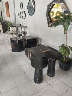 several tables and stools are lined up against the wall with mirrors on it, along with plants