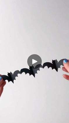 two hands holding an origami bat that looks like it is flying through the air