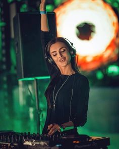 a woman wearing headphones is playing music on a dj's turntable in front of a green background