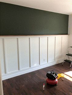 a room with hard wood flooring and green paint on the wall, including a red vacuum