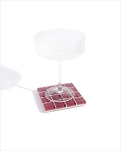 a red and white table with a glass on it's base that is shaped like a bowl