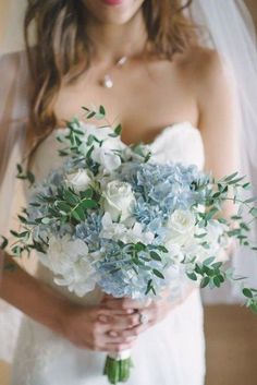 a bride holding a bouquet of blue and white flowers