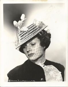 an old black and white photo of a woman wearing a hat with flowers on it