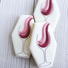 three decorated cookies sitting next to each other on top of a wooden table with white and red icing