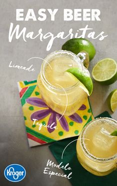 two margaritas sitting on top of a table next to limes and a napkin