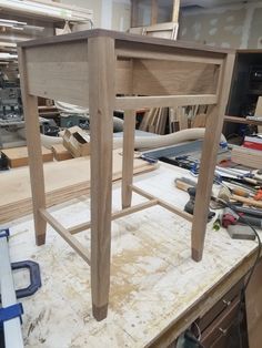 a wooden chair sitting on top of a table in a room filled with woodworking tools