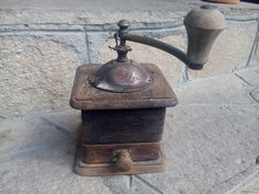 an old fashioned coffee grinder sitting on top of a stone wall