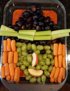 grapes, carrots, celery and apples arranged in the shape of a face