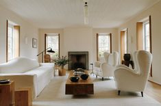 a living room filled with white furniture and lots of windows in it's walls