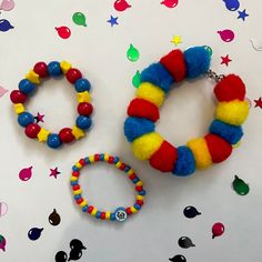 two colorful bracelets and a keychain on a white table with confetti