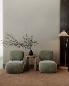 two green chairs sitting next to each other in front of a lamp on a table