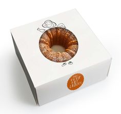 a white box with an orange ribbon around the bottom and inside, containing a bundt cake