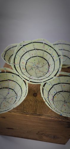 four woven baskets sitting on top of a wooden table