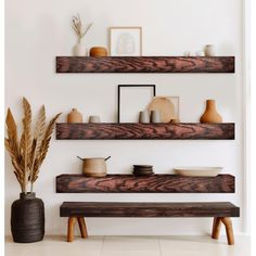 three wooden shelves with vases and other items on them in a white living room