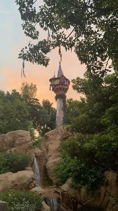 there is a tower with a waterfall in the middle of it and trees around it