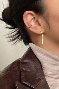 a close up of a person with ear piercings on their ears and wearing a leather jacket