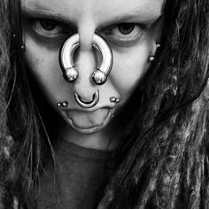 a woman with long hair and piercings on her nose is wearing a fake nose ring