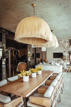 a large wooden table topped with white vases filled with flowers next to a couch