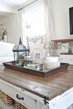 a tray with books on top of a wooden table in front of a tv and window