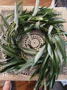 a wreath made out of green leaves on top of a doily with a person's feet in the background