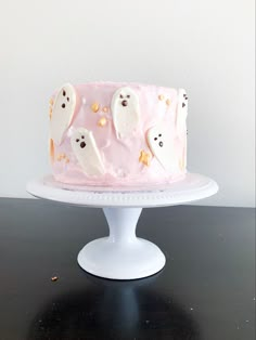 a pink frosted cake with ghost decorations on it