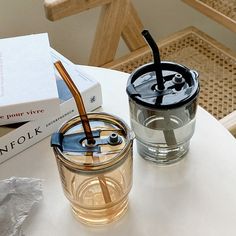 a glass with a straw in it sitting on a table next to some books and a drink