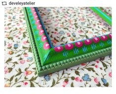 a close up of a green frame on a floral tablecloth with pink and blue designs