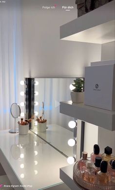 a white counter top sitting under a mirror with lights on it's sides and bottles in front of it