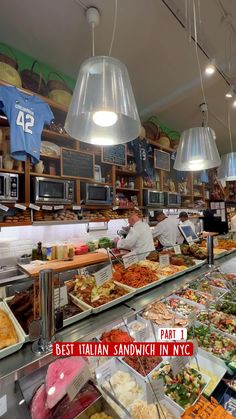 an italian restaurant with many different types of food on the counter and hanging lights above it