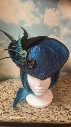 Beautiful Teal Victorian Inspired Hat with a Black Rose, Peacock and Black Feathers. Perfect for dressing up, formal events, Vampire Balls, and cosplay. Other styles are available in all colors. Message me for a custom order. Made in a pet friendly studio. Made to order. 3 to 5 days creation time. Check out my other listings: Black Velvet Victorian with Tassels: https://www.etsy.com/listing/1197594531/black-velvet-formal-hat-velvet-top-hat Silver Victorian: https://www.etsy.com/listing/1293744756/victorian-hat-edwardian-hat-downton Mauve Victorian:  https://www.etsy.com/listing/1293745798/mauve-velvet-hat-formal-hat-red-top-hat Burgandy Victorian:  https://www.etsy.com/listing/1094341893/victorian-hat-edwardian-hat-downton Turquoise Peacock: https://www.etsy.com/listing/1101444884/turquois Rococo Hat, Peacock Hat, Pirate Captain Hat, Fantasy Hat, Steampunk Hats, Tea Hat, Teal Hat, Hat With Feather, Mauve Velvet