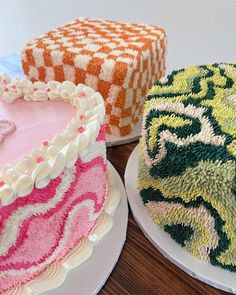 three cakes with different designs on them sitting on plates