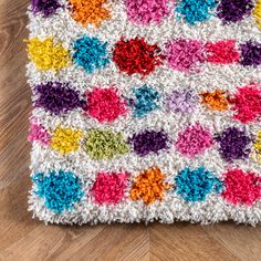 a multicolored crocheted afghan on a wooden floor, with the pattern in different colors