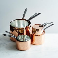 several pots and pans are lined up on a counter top with utensils in them