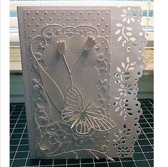 a white card with an intricate design on the front and side, sitting on a table next to a window