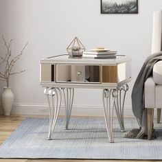 a living room with a couch, chair and mirrored end table in the middle of it