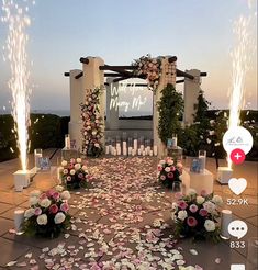 an outdoor wedding setup with flowers and candles on the ground at night, in front of a movie screen