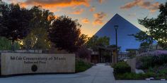 the entrance to the museum is lit up at sunset with colorful clouds in the background