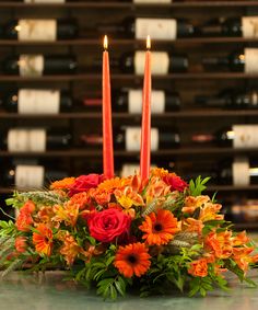 an arrangement of flowers and candles on a table