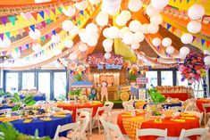 a room filled with lots of tables covered in white and orange cloths