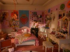 a woman sitting on top of a bed in a room with lots of clutter