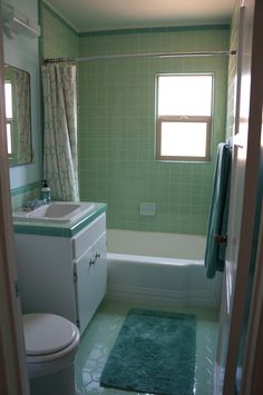 a bathroom with green tile and white fixtures